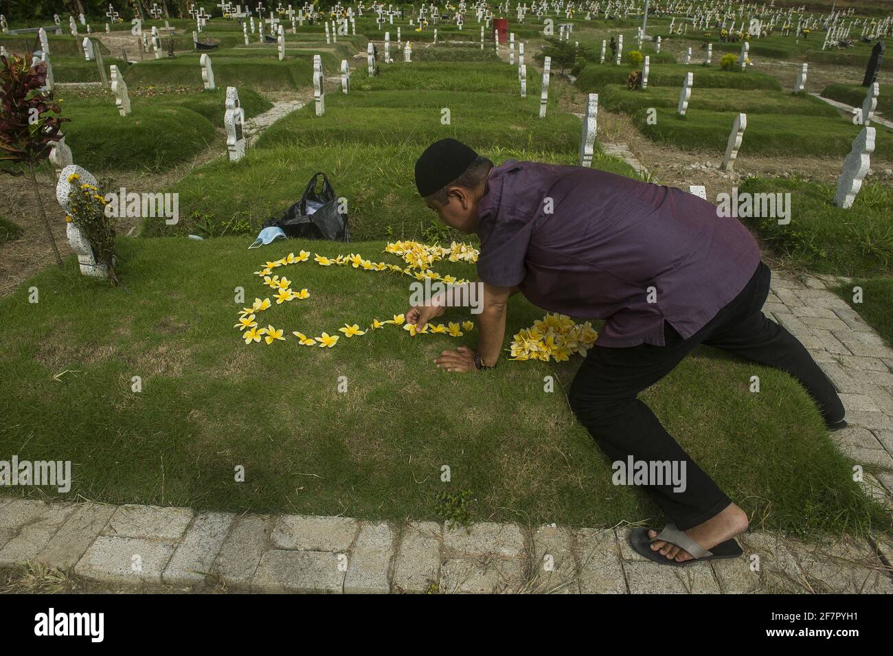 Medan, Indonesia. 09th Apr, 2021. A man, Hanafi, 42, seen make flower as love to carrying out the tradition of a funeral pilgrimage to welcome the holy month of Ramadan 1442H at specific cemetery for coronavirus pandemic victims in Medan, Indonesia on April 9, 2021. Hanafi admitted to being sad and traumatized were remembering 9 months ago moment, when his wife died due coronavirus disease-19 in the same time with Eid Al-Fitr 2020. Photo by Sutanta Aditya/ABACAPRESS.COM Credit: Abaca Press/Alamy Live News Stock Photo