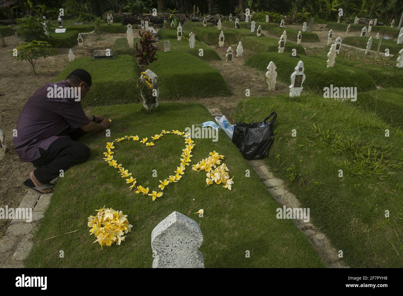 Medan, Indonesia. 09th Apr, 2021. A man, Hanafi, 42, seen make flower as love to carrying out the tradition of a funeral pilgrimage to welcome the holy month of Ramadan 1442H at specific cemetery for coronavirus pandemic victims in Medan, Indonesia on April 9, 2021. Hanafi admitted to being sad and traumatized were remembering 9 months ago moment, when his wife died due coronavirus disease-19 in the same time with Eid Al-Fitr 2020. Photo by Sutanta Aditya/ABACAPRESS.COM Credit: Abaca Press/Alamy Live News Stock Photo