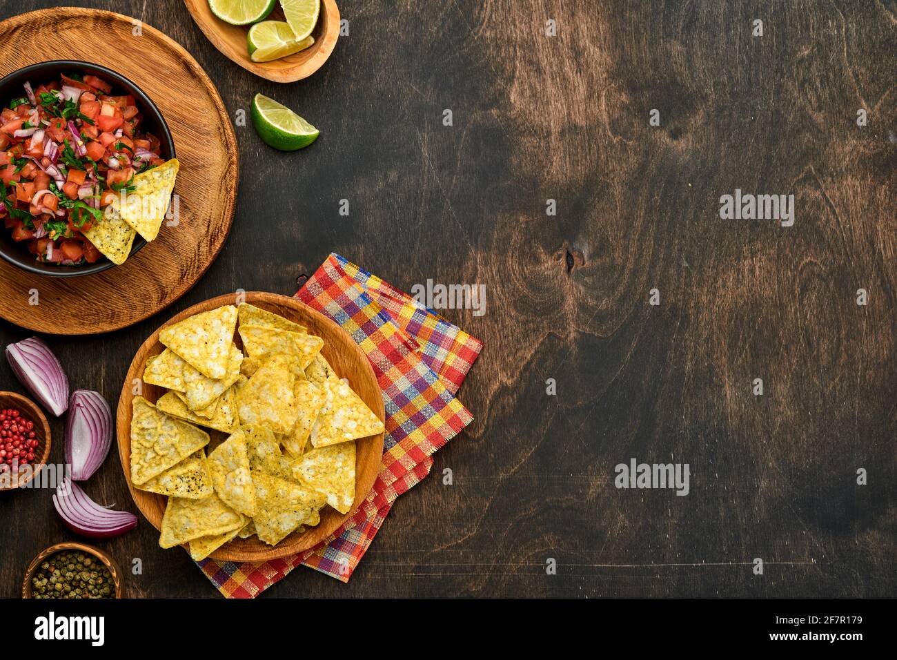Traditional Mexican tomato sauce salsa with nachos and ingredients tomatoes, chile, garlic, onion on dark old wooden background. Concept of Latin Amer Stock Photo