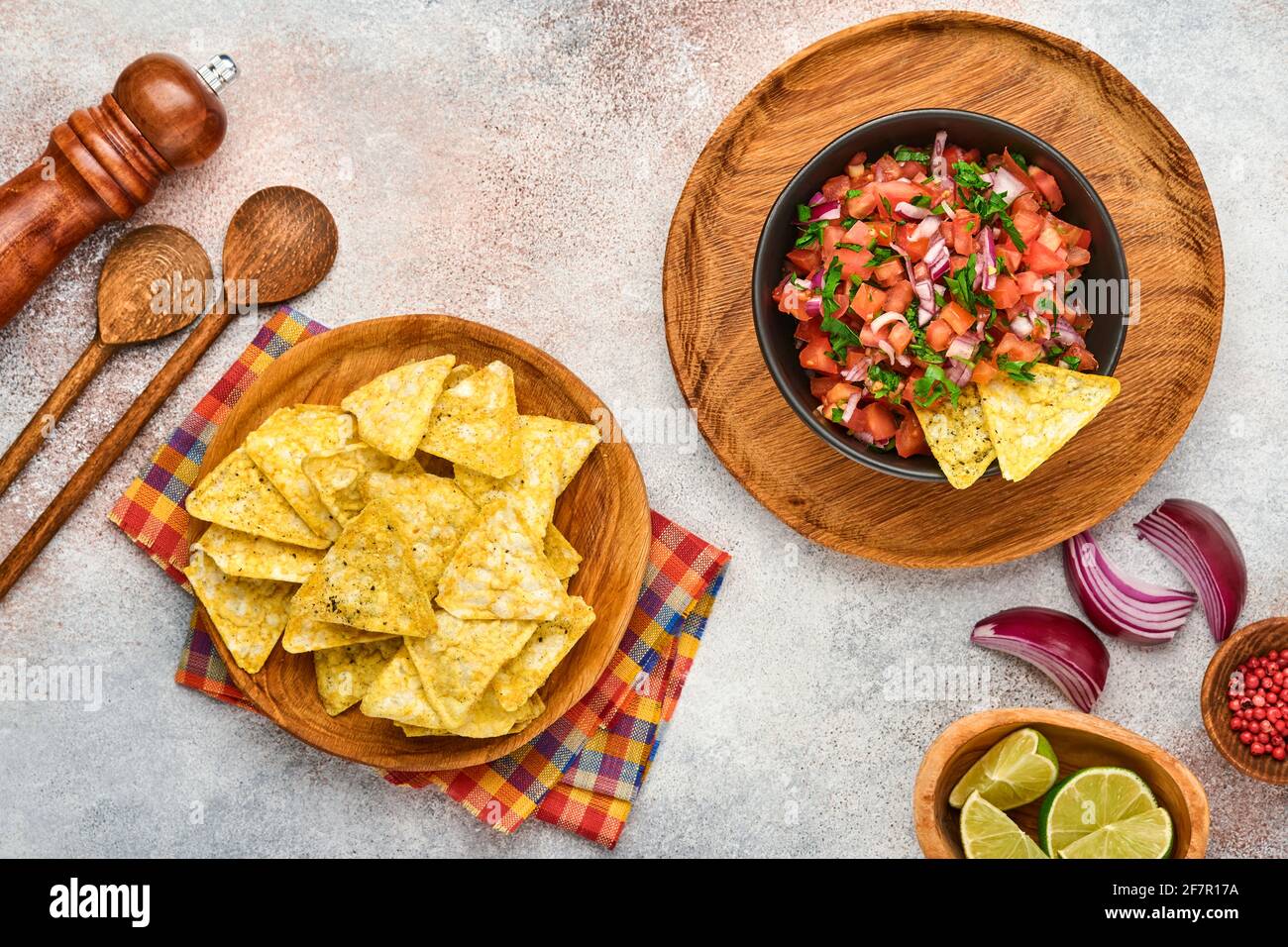 Traditional Mexican tomato sauce salsa with nachos and ingredients tomatoes, chile, garlic, onion on light slate stone background. Concept of Latin Am Stock Photo