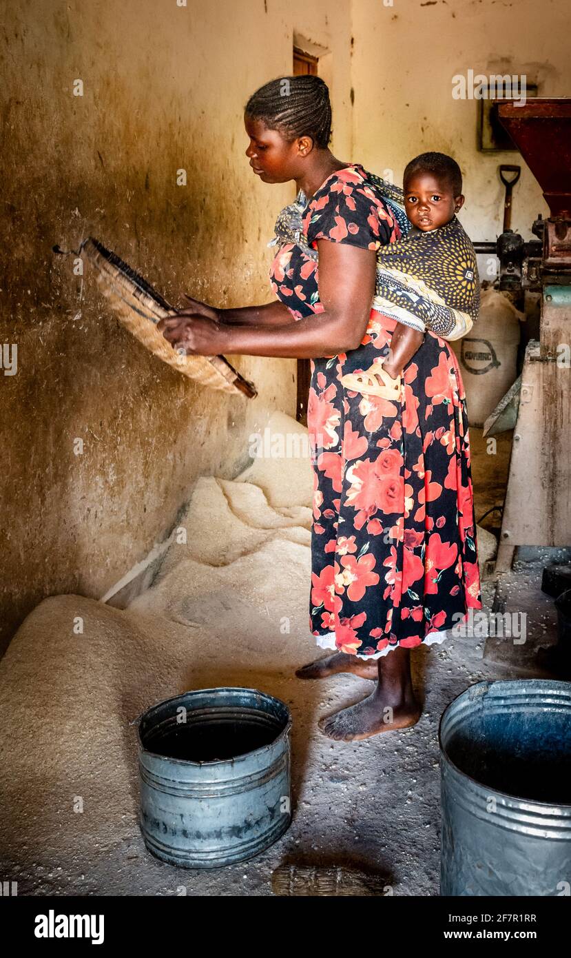 Young African mother sifting maize flour after grain has been milled Stock Photo