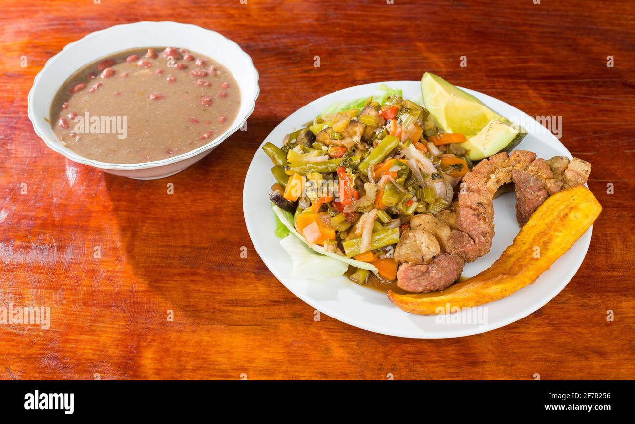 Pork greaves with vegetable salad, fried plantain and beans Typical