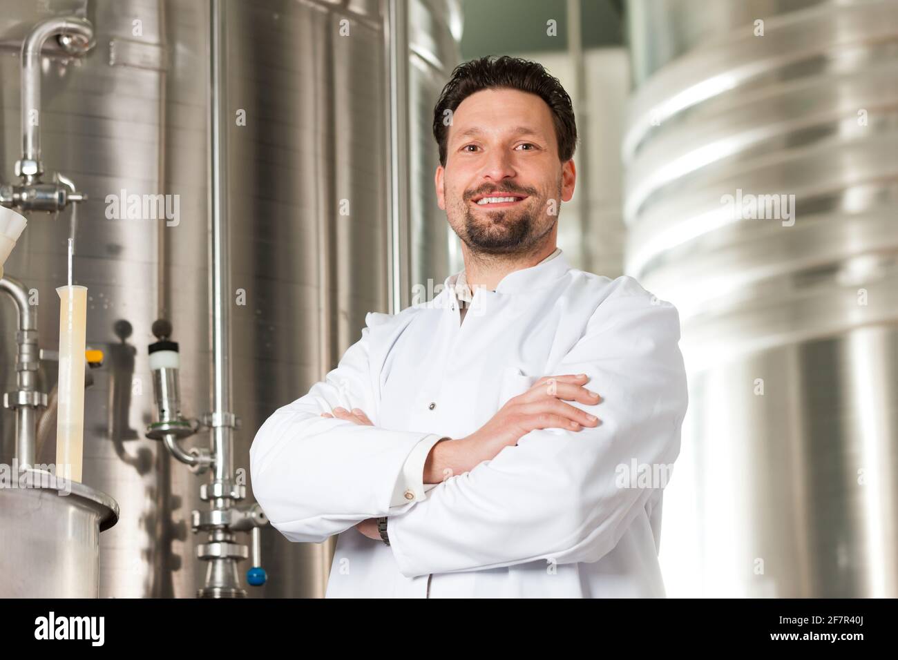 Brewer standing in his brewery in front of a stainless copper fermenter Stock Photo