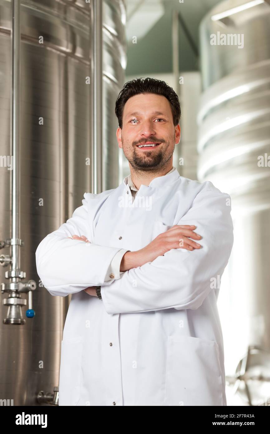 Brewer standing in his brewery in front of a stainless fermenter Stock Photo