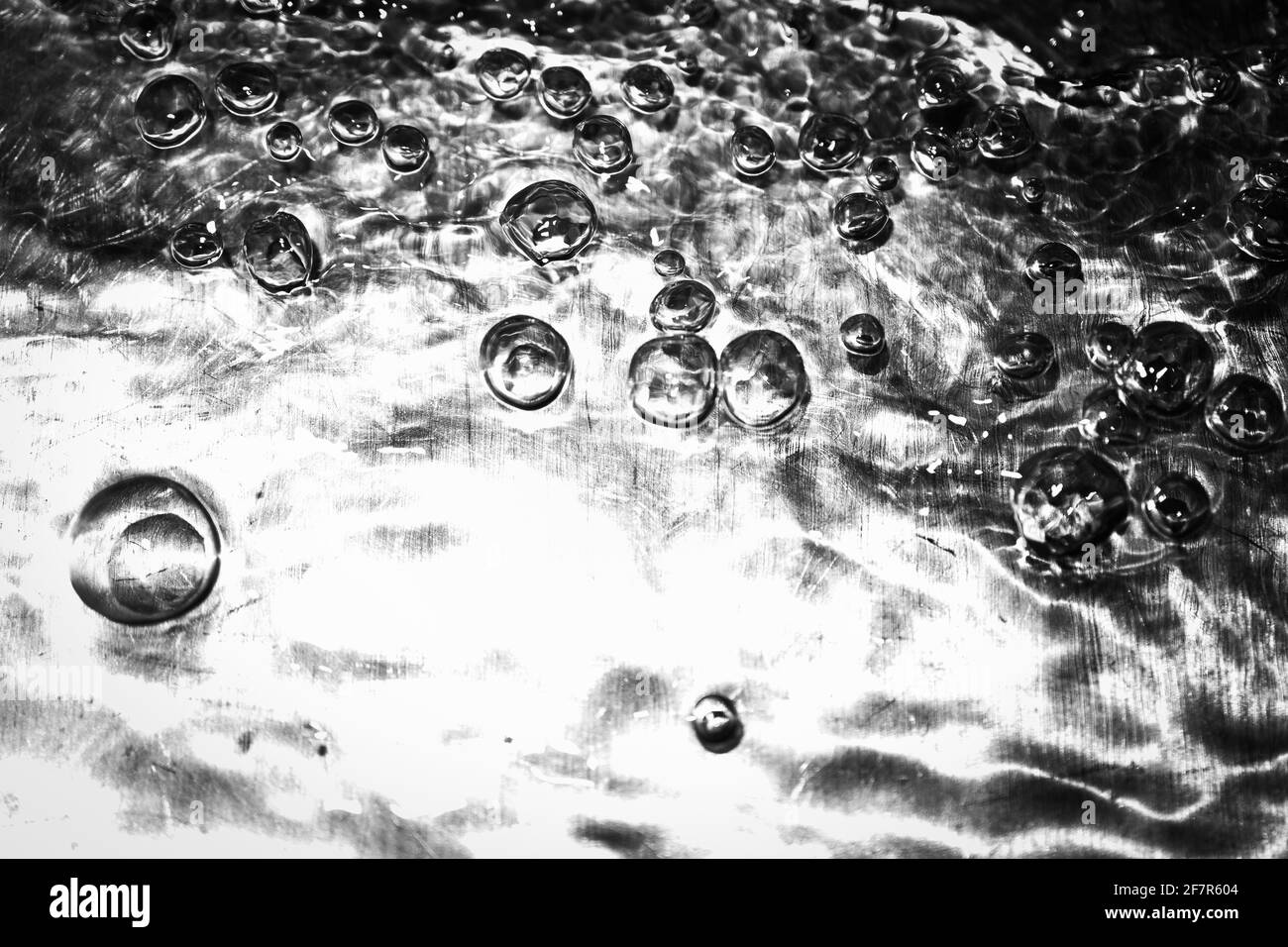 Extreme close up of moving water and bubbles with high contrast on metalic surface Stock Photo
