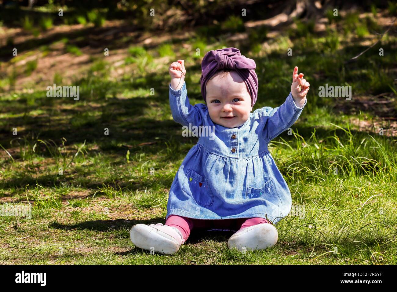 Cute baby girl outdoor in spring time on grass with hands up Stock ...