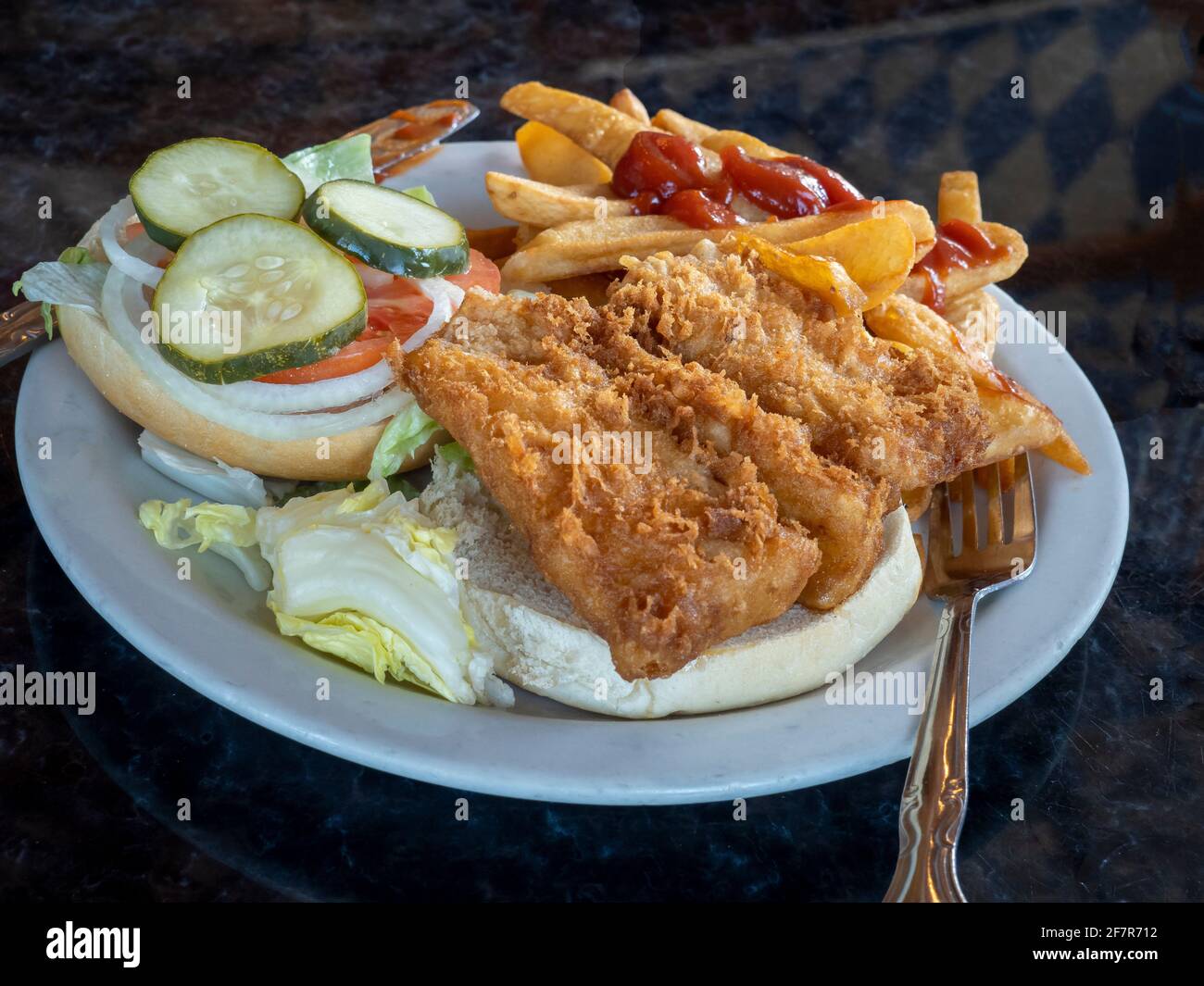 Lunch of Fried fish sandwich with french fries on light blue plate Stock Photo