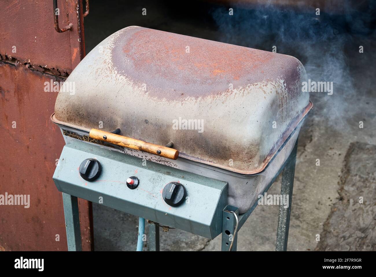 Rusty barbecue lit with closed lid and smoke coming out Stock Photo Alamy