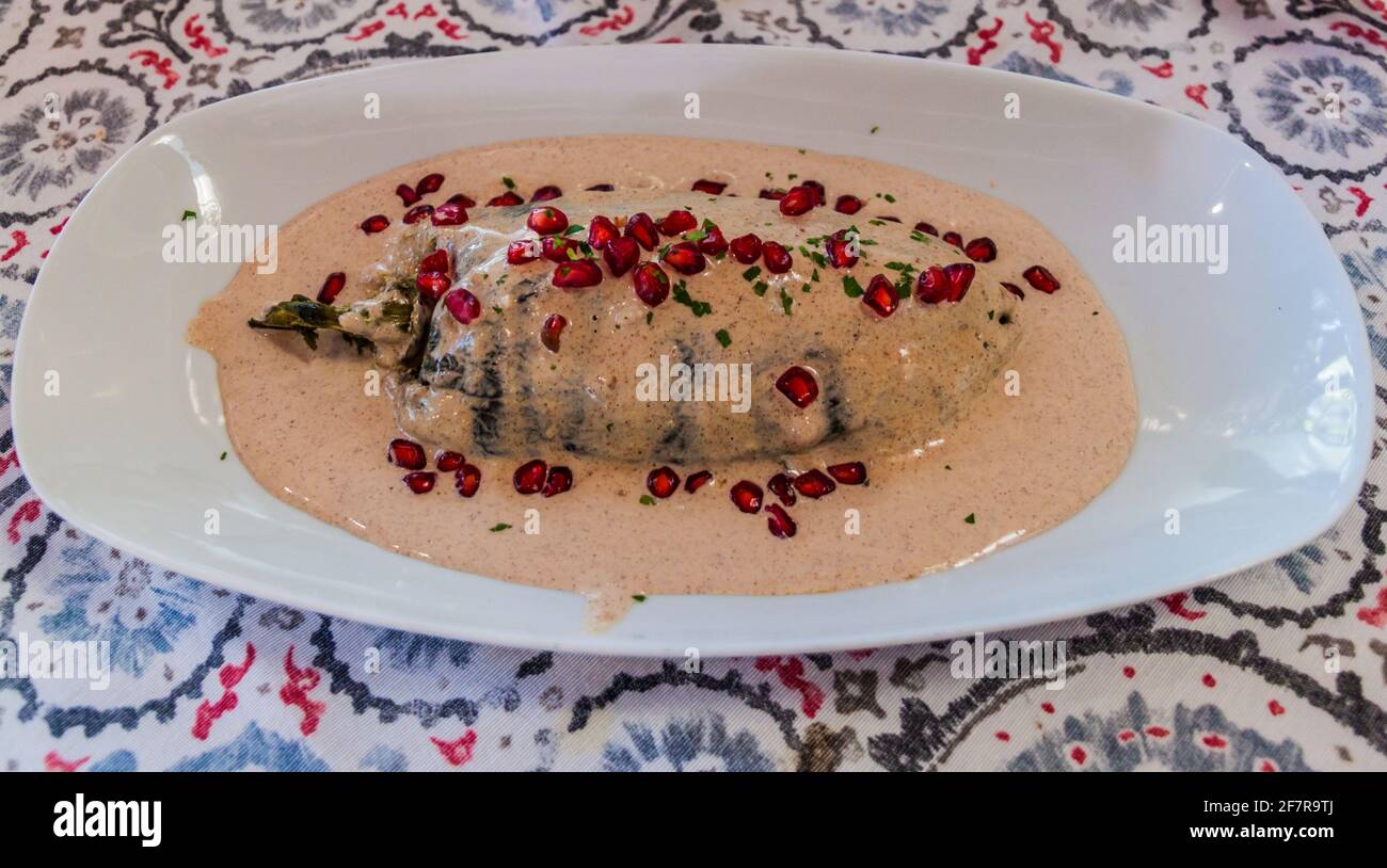 Mexican dish, chiles en nogada. Stuffed poblano peppers in walnut sauce with pomegranate seeds. Stock Photo