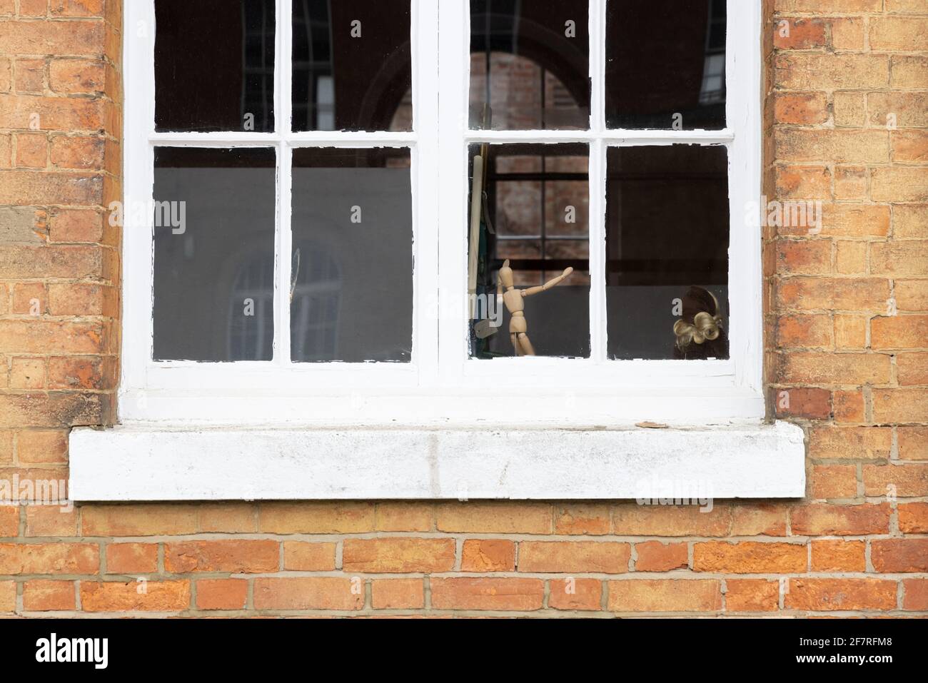Weedon, Northamptonshire, UK - March 18th 2021: A wooden artist's mannequin appears to be dancing by a white, wooden-framed sash window. Stock Photo