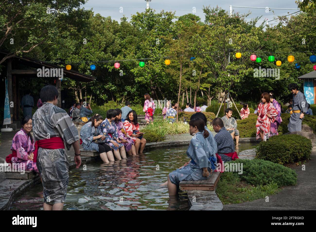 Horizontal view of a group of people wearing yukata soaking and relaxing in Oedo-Onsen Monogatari outdoor rotenburo baths, Koto City, Odaiba Island Stock Photo
