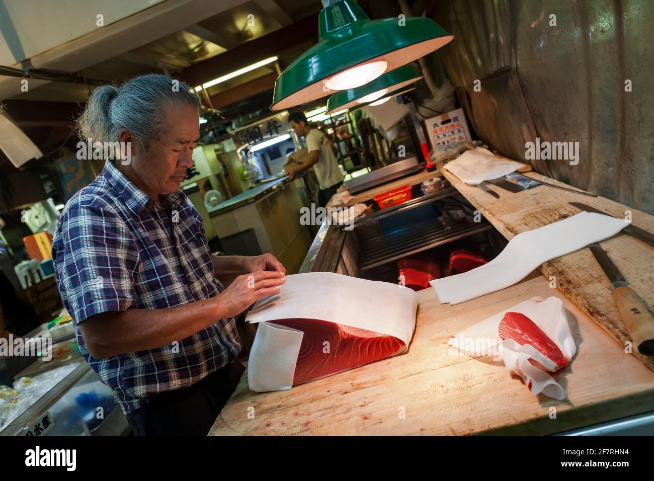 Japanese fishmonger wrapping a piece of red tuna with paper in the Seafood Intermediate Wholesalers' Area interior, Tsukiji Market, Tokyo, Japan Stock Photo