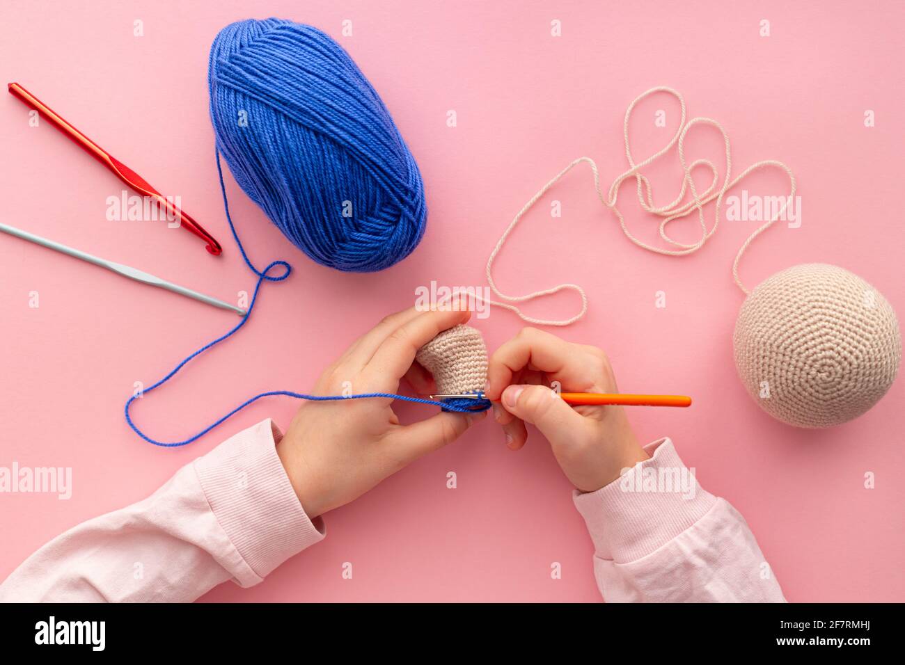 Children's hands in the process of crocheting toys from blue and beige