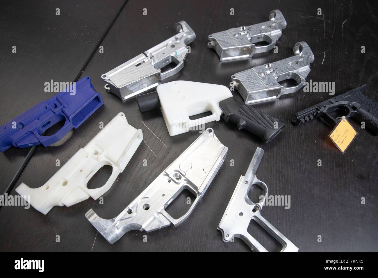 Metal and plastic 3D printed gun parts lie on a table at the office of