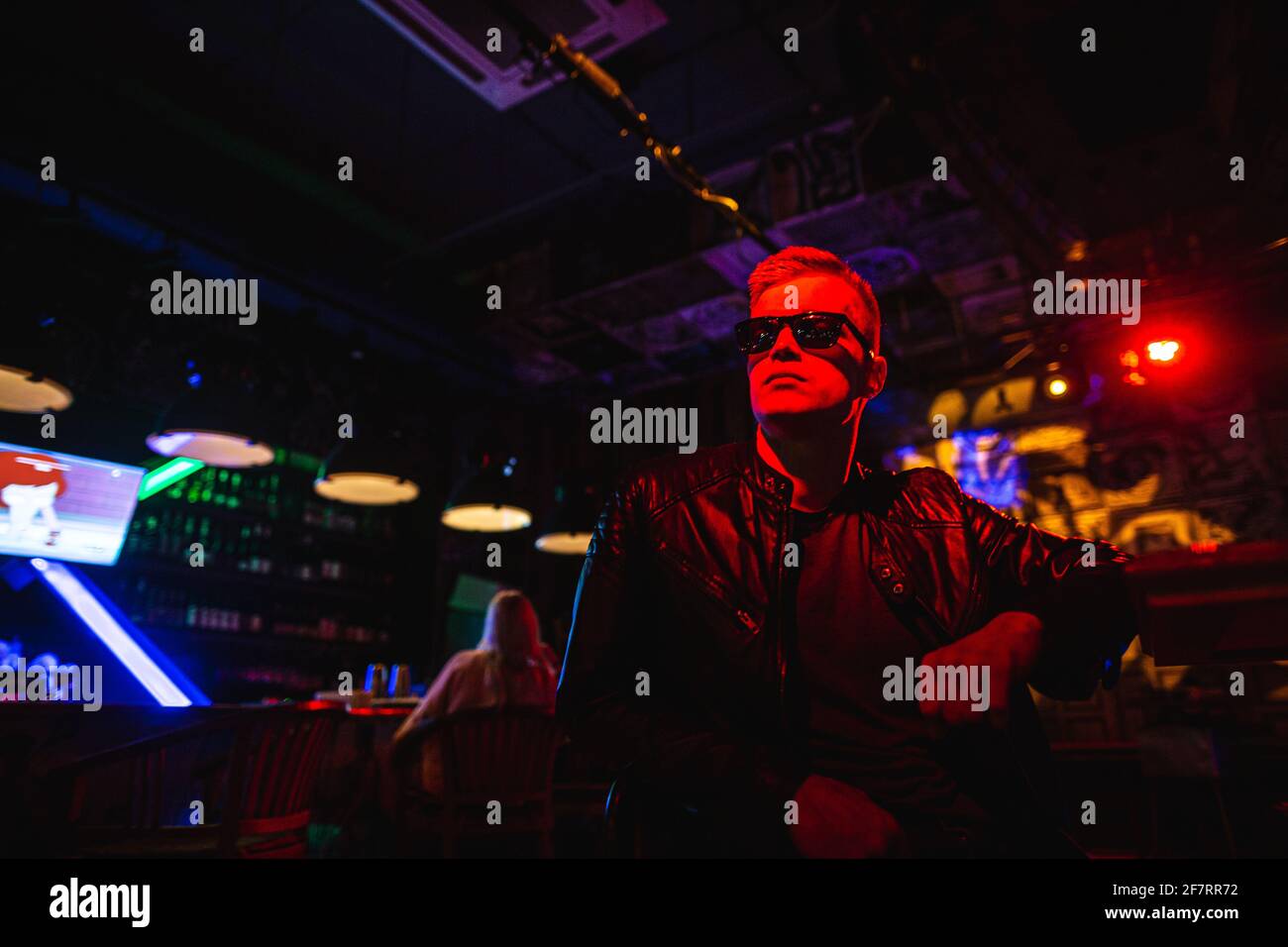 Handsome man in leather jacket with sunglasses and neon lights. Stock Photo