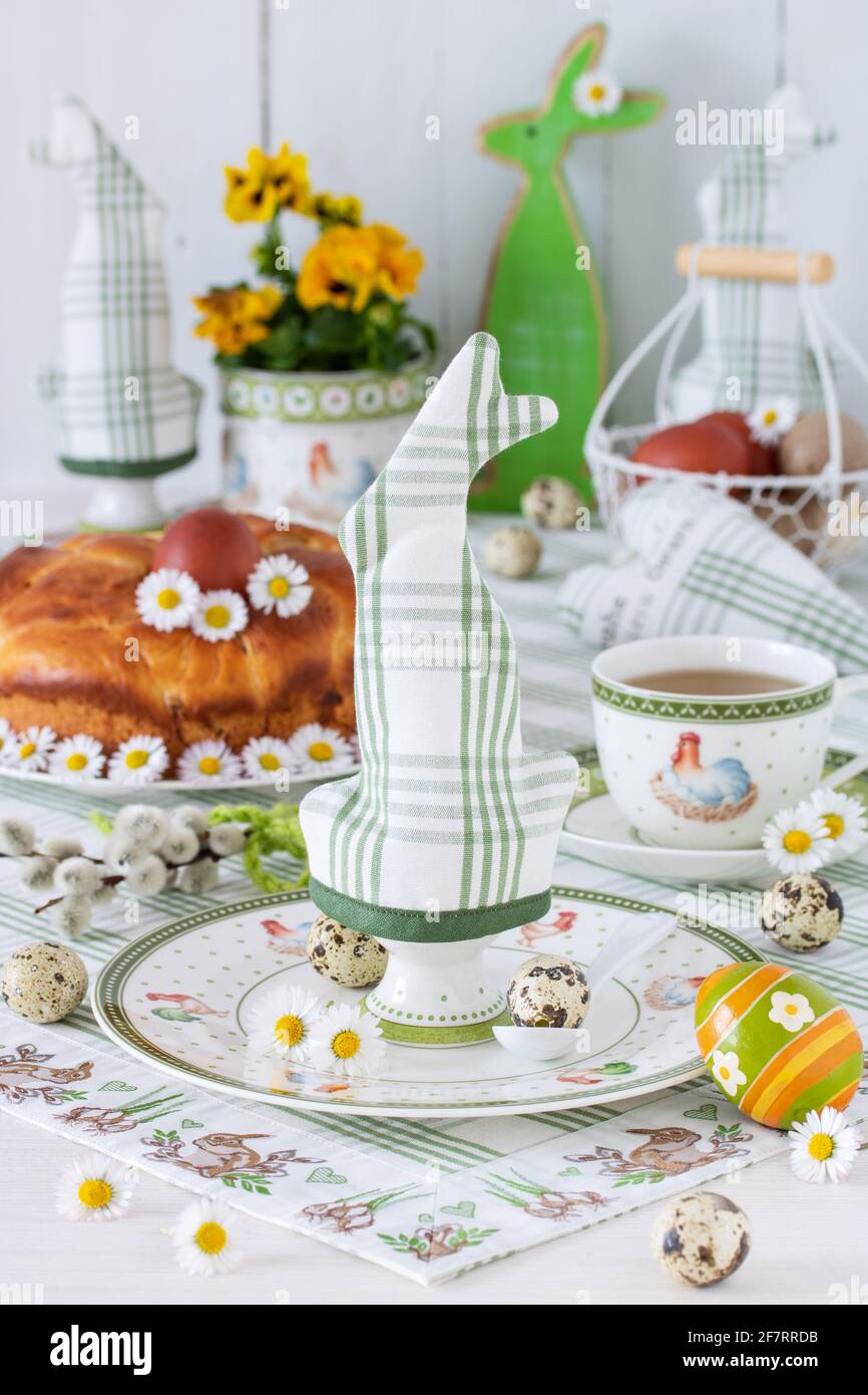 easter table decoration with egg cosy, yeast wreath, easter eggs and flowers Stock Photo