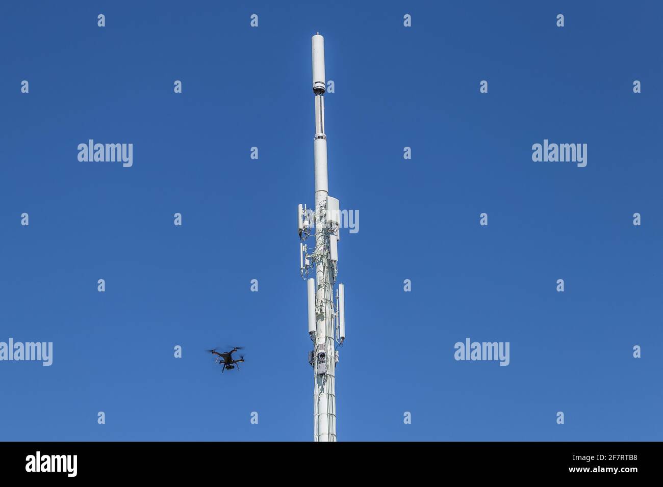 Drone inspecting a cell tower on the lower left Stock Photo