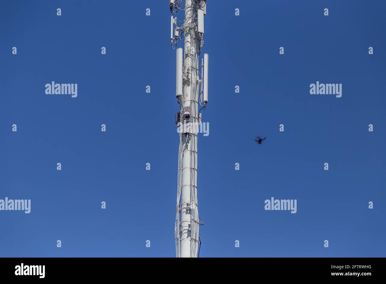 Drone inspecting a cell tower on the lower right Stock Photo