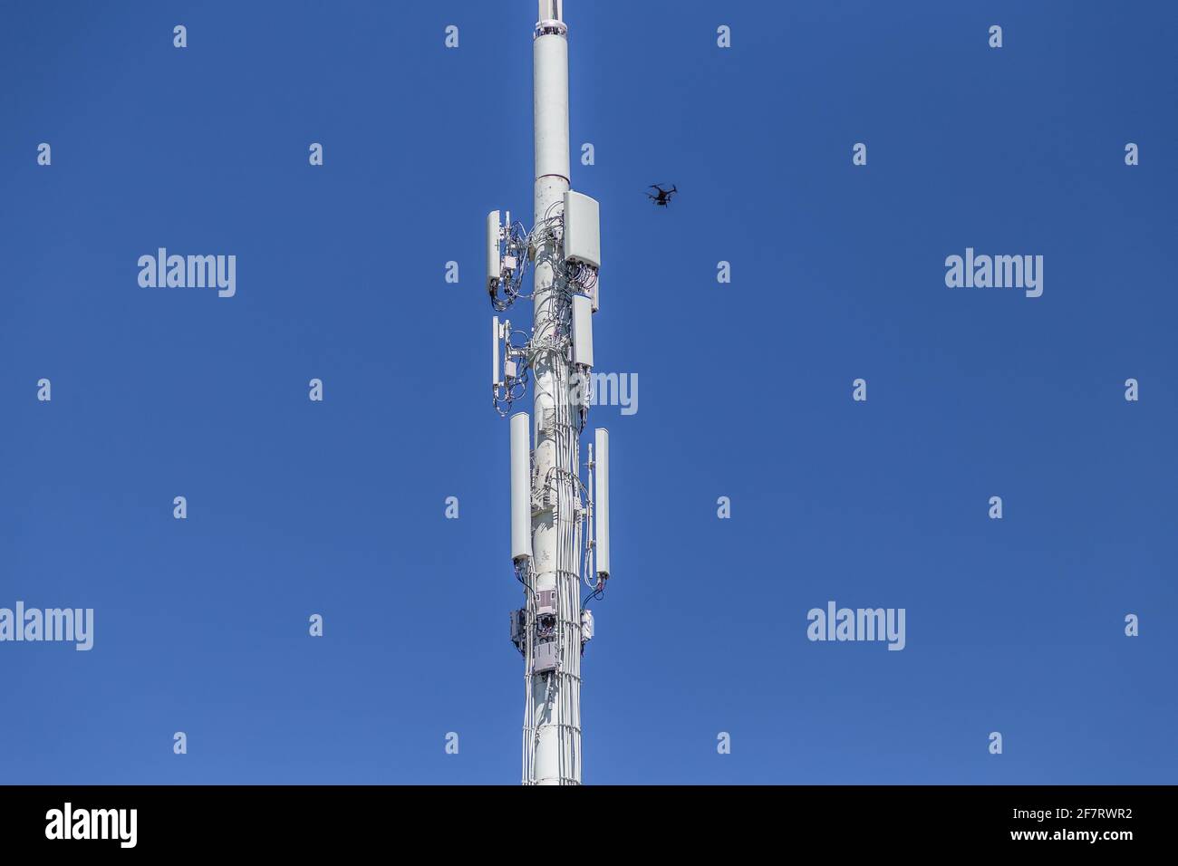 Drone Inspecting right top section of a cell tower Stock Photo