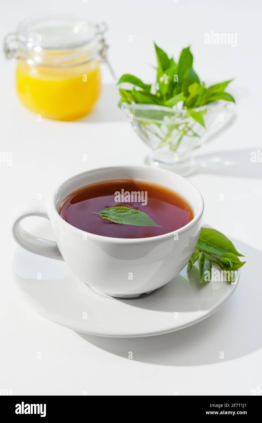 Cup of hot tea with lemongrass leaves and honey, on a white background. Shallow depth of field Stock Photo