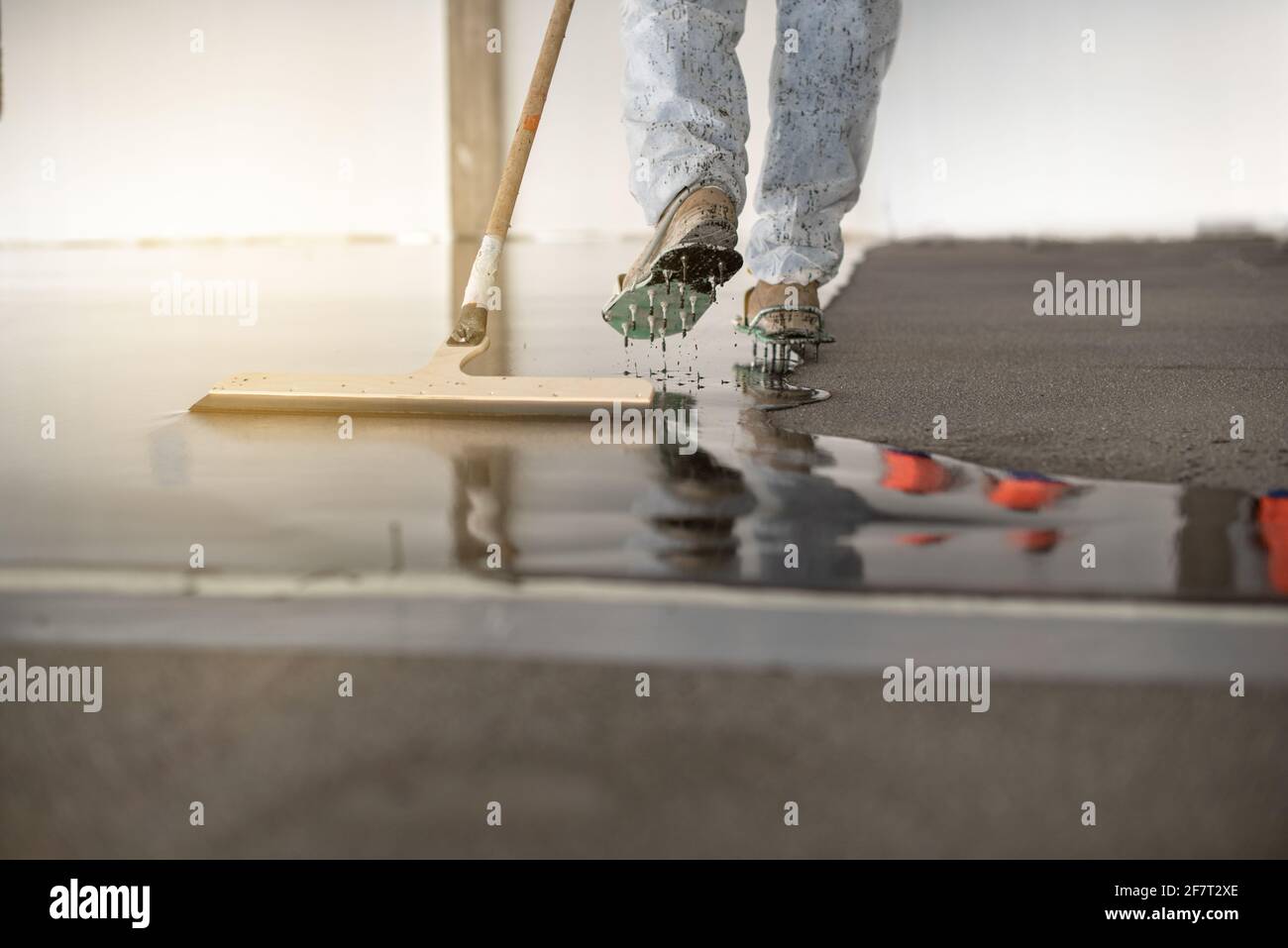 Worker working on the floor of an industrial building. Construction worker producing grout and