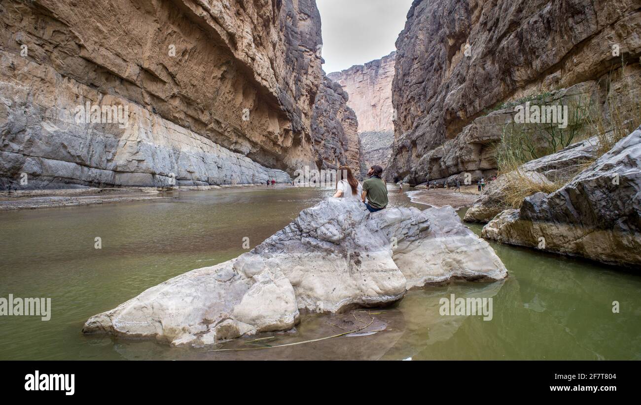 A couple sits on a rock and enjoys the views from down inside Santa Elena, Canyon in Big Bend National Park, TX Stock Photo