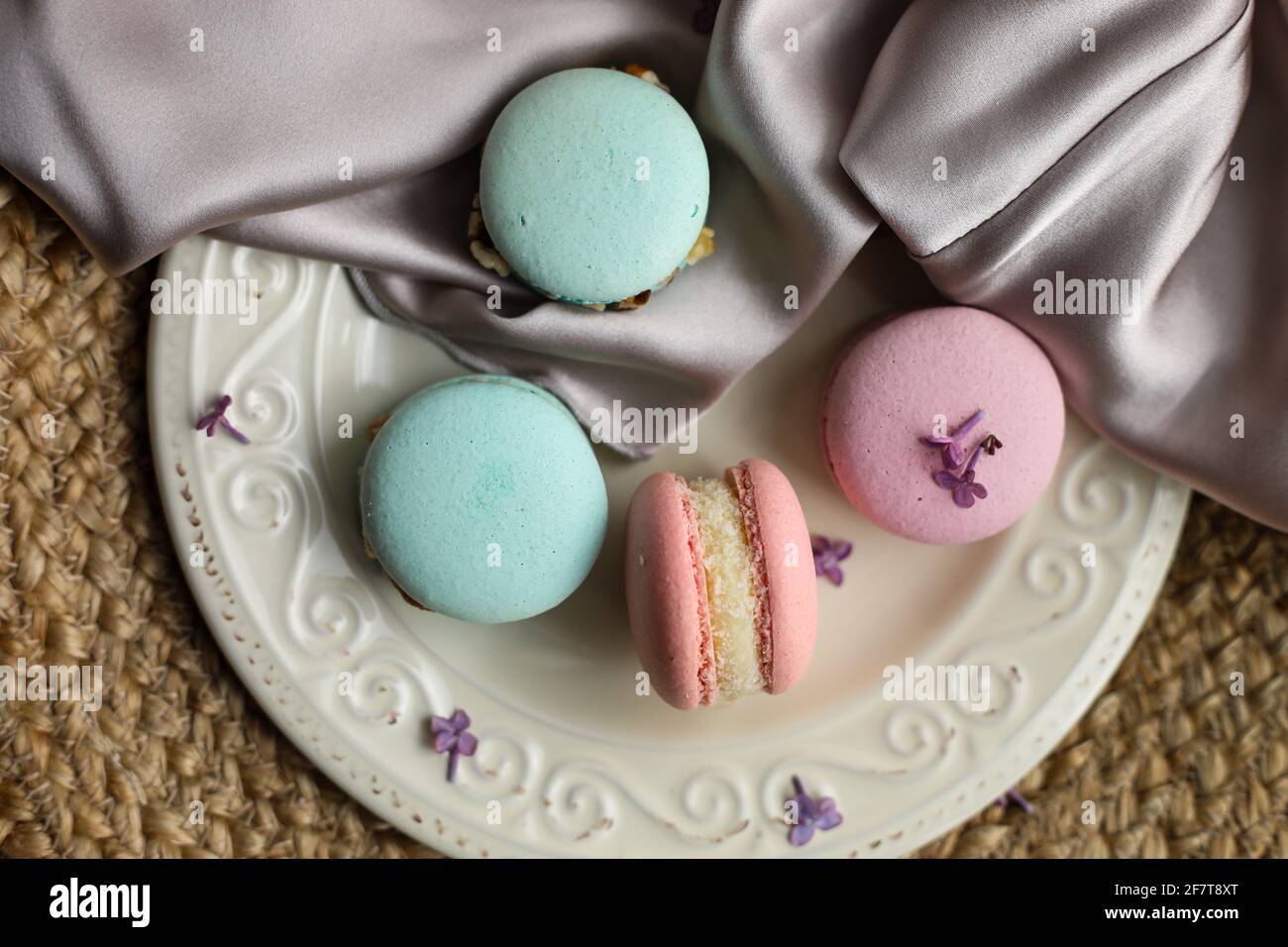 colorful french dessert macaroons or macarons on a plate with lilac flower  on a straw and atlas cloth background Stock Photo - Alamy