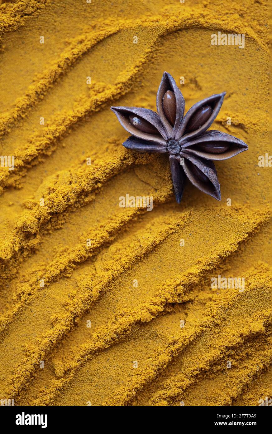 Anise star on turmeric sand, yellow curcuma Stock Photo