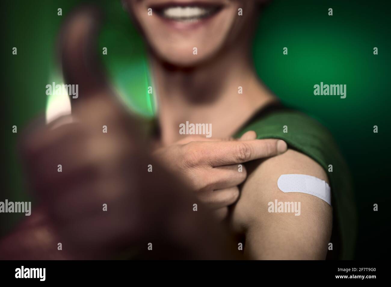 Vacinee person with plaster on arm after vaccination thumbs up for virus immunization inoculation injection Stock Photo
