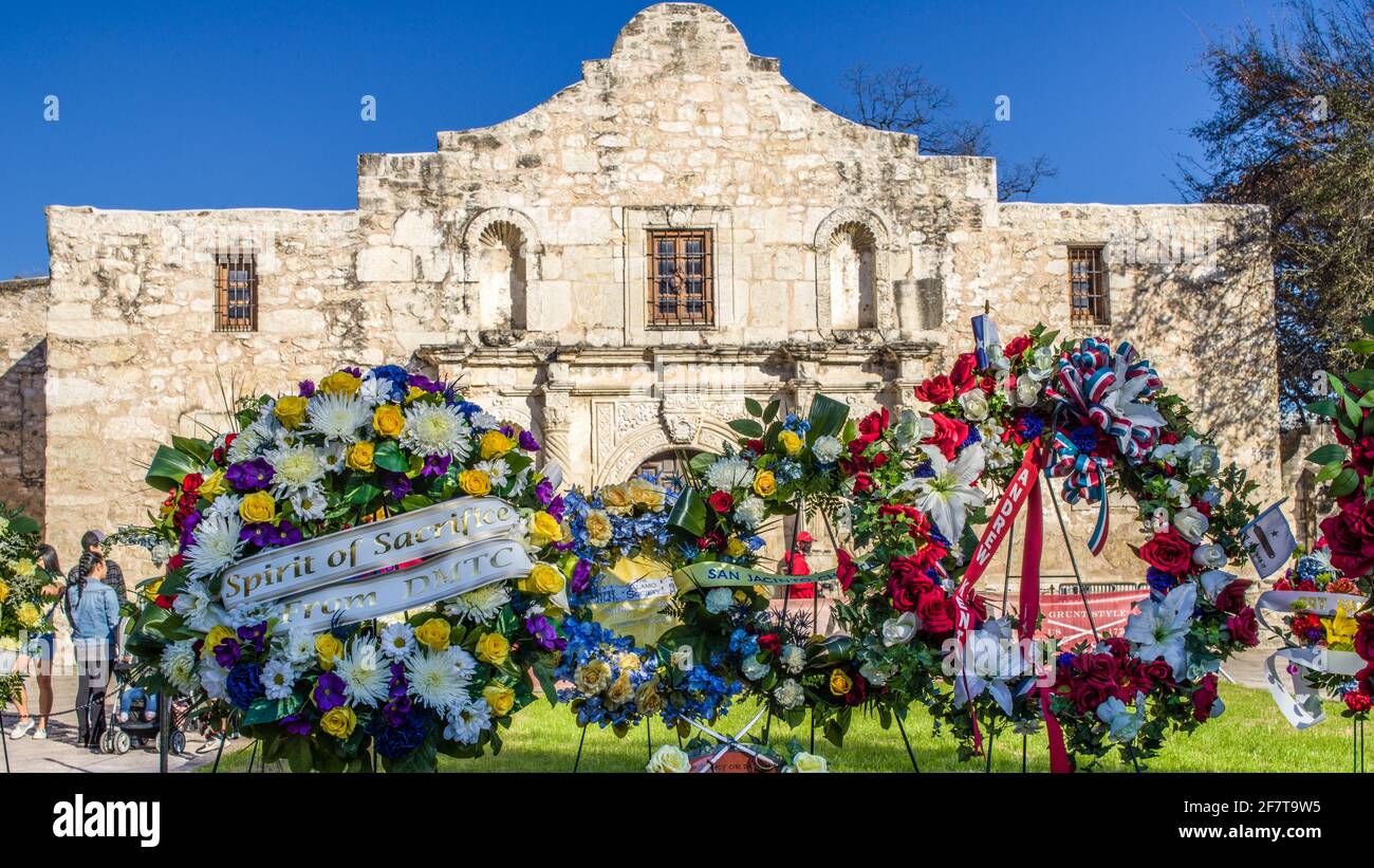 Wreaths of flowers place out in front of the iconic facade of the Alamo