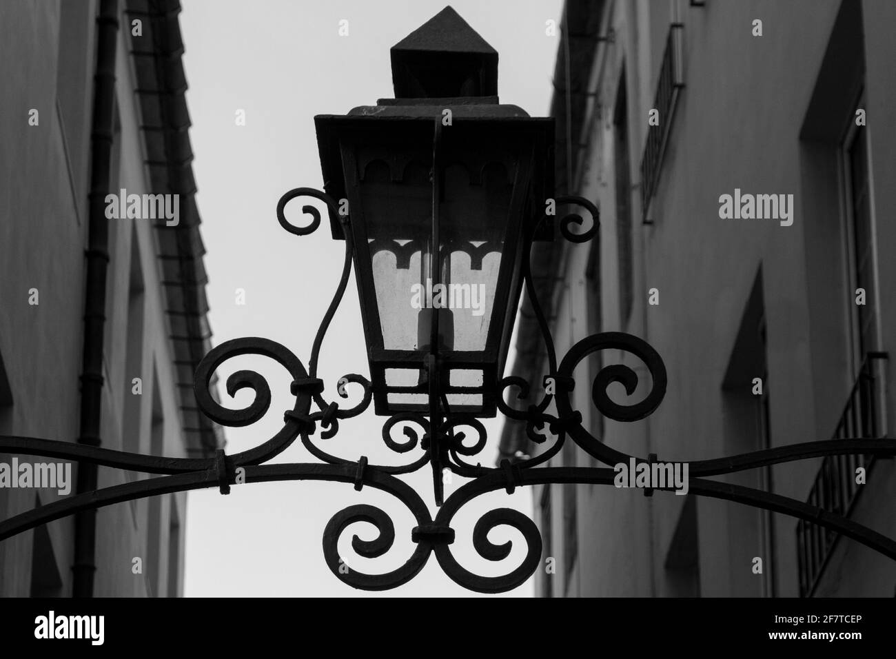 Detail of an old metal lamp in a metal frame on a narrow street Stock Photo