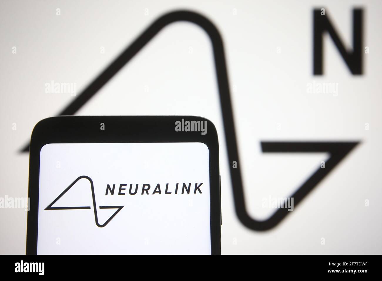 In this photo illustration a Neuralink logo is seen on a smartphone and a pc screen. Stock Photo