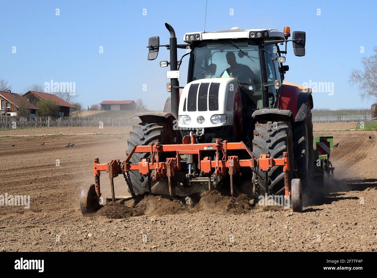 Tractor Ploughing And Sowing Seeds Onto An Agricultural Field On A Sunny Day At The Start Of The