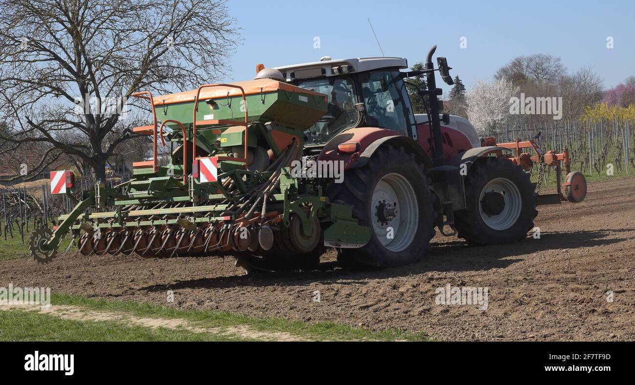 Tractor Ploughing And Sowing Seeds Onto An Agricultural Field On A Sunny Day At The Start Of The