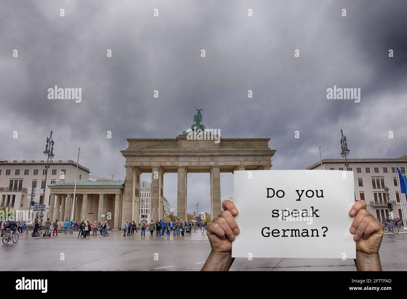 a man holding a sign with the Brandenburg Gate in Berlin in the background Stock Photo