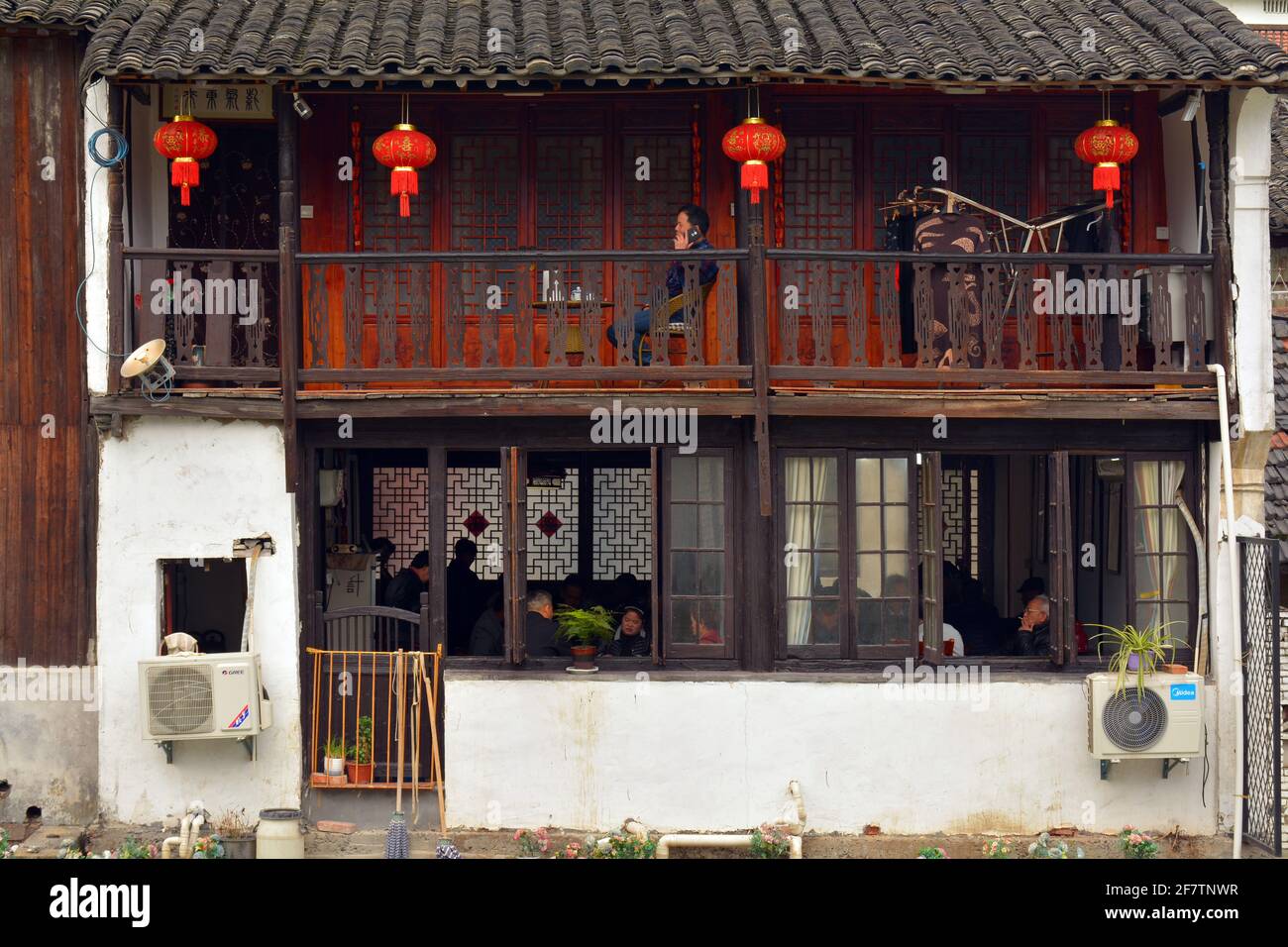Everyday scene in a local Chinese community. This old building has many people doing different things both upstairs and downstairs. Stock Photo