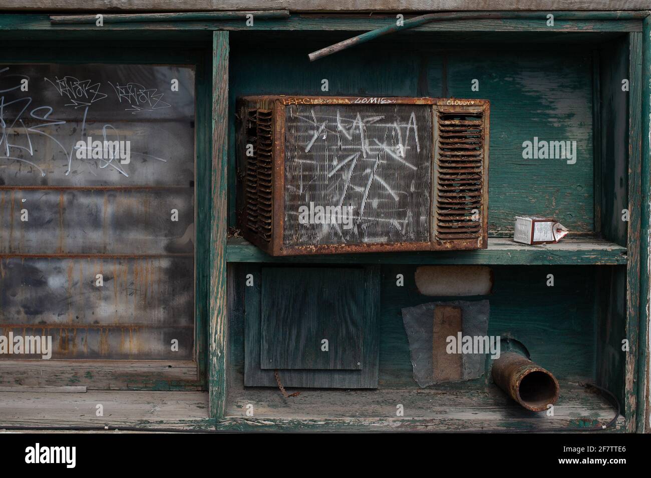 Rusty, old air conditioner unit on broken down, teal shelf. Stock Photo