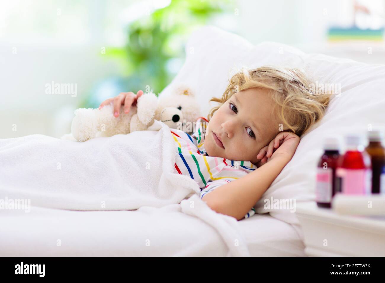 Sick little boy with asthma medicine. Ill child lying in bed. Unwell