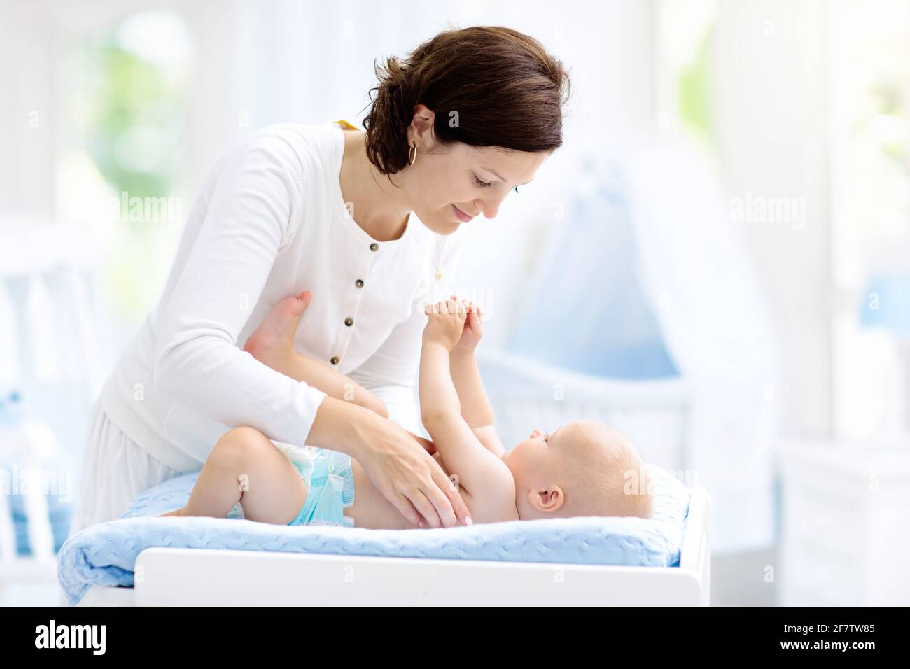 Mother and baby in diaper on changing table. Mom changing nappy on baby boy. Kids nursery