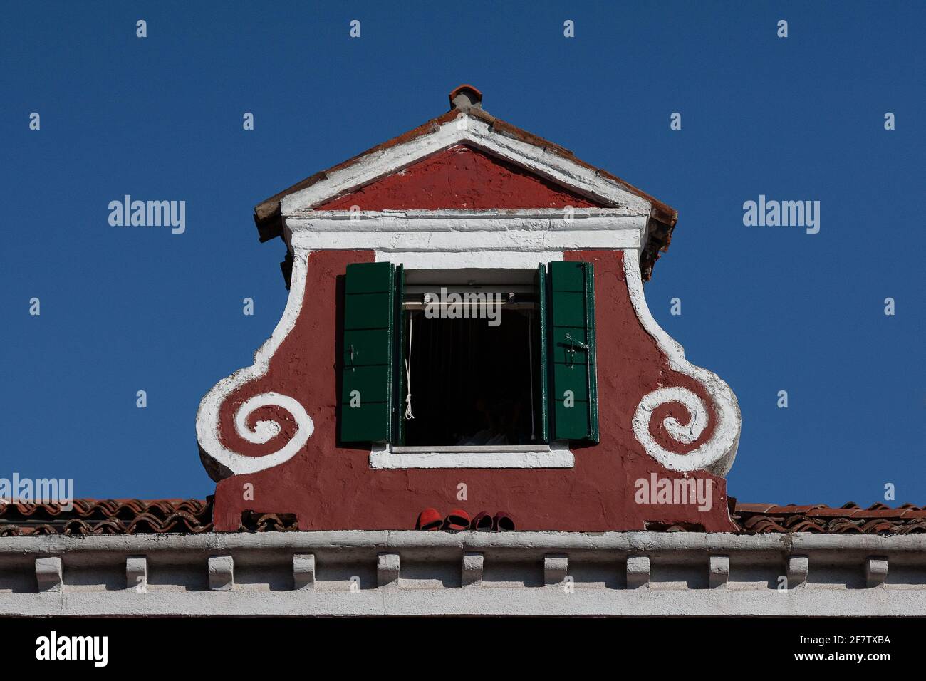 View of an atique window in an Italian house in Burano, Italy against a clear blue sky background Stock Photo