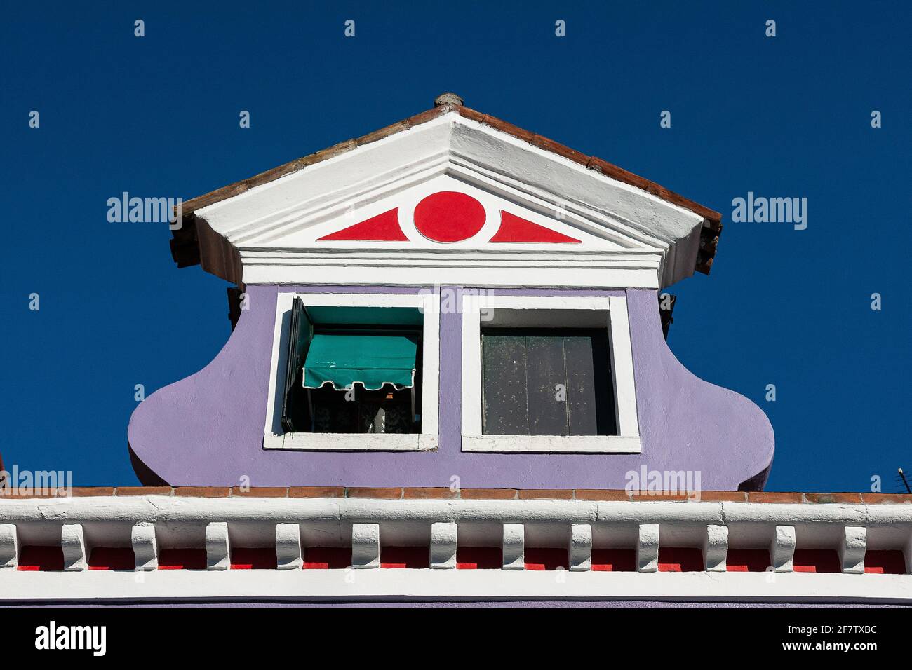 View of an atique window in an Italian house in Burano, Italy against a clear blue sky background Stock Photo