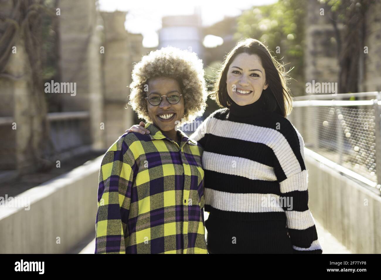 Happy African-American and Caucasian female friends hugging each other ...
