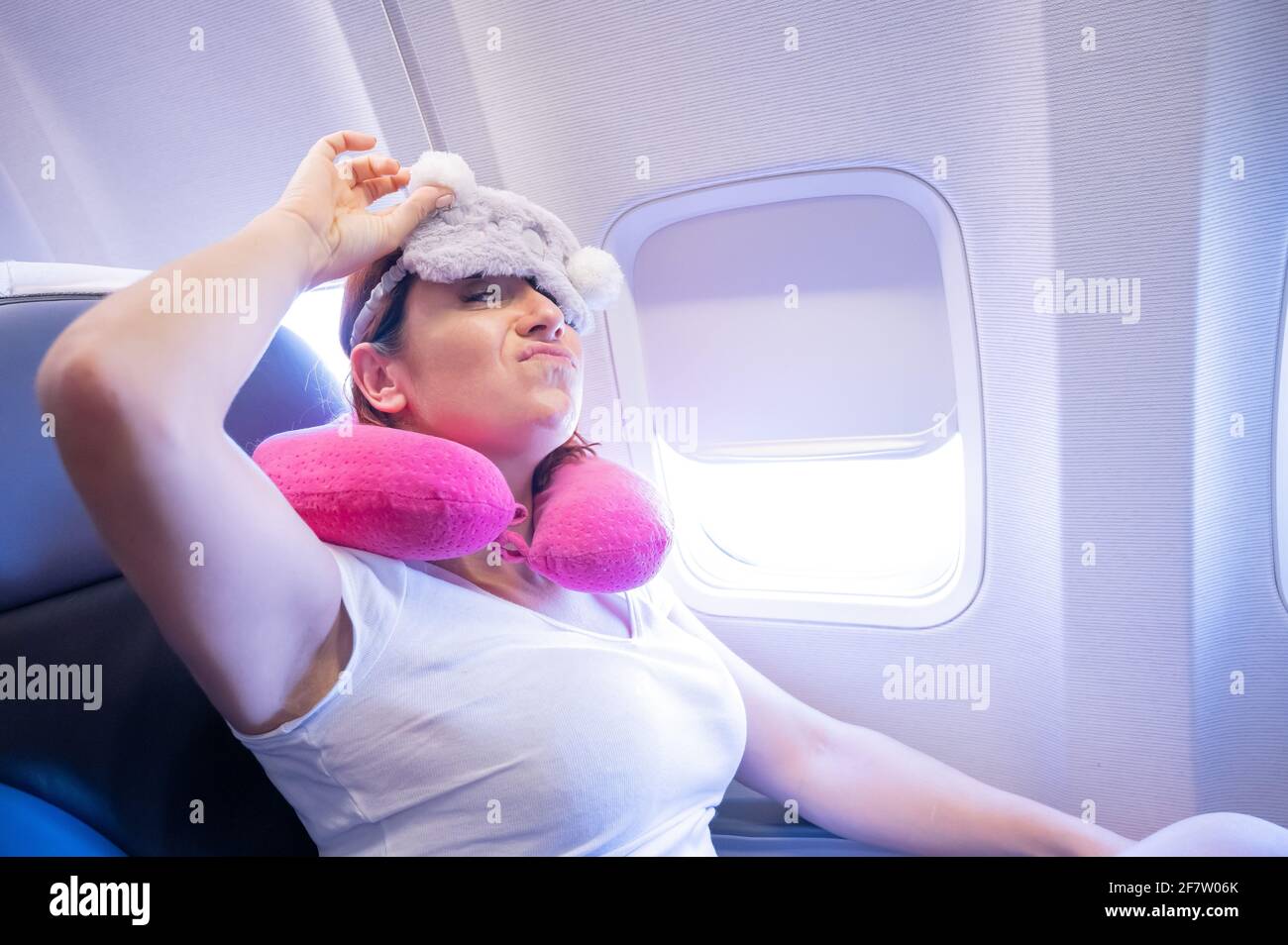 Tired redhaired woman sleeping on the plane with an eye mask and a neck pillow Stock Photo Alamy