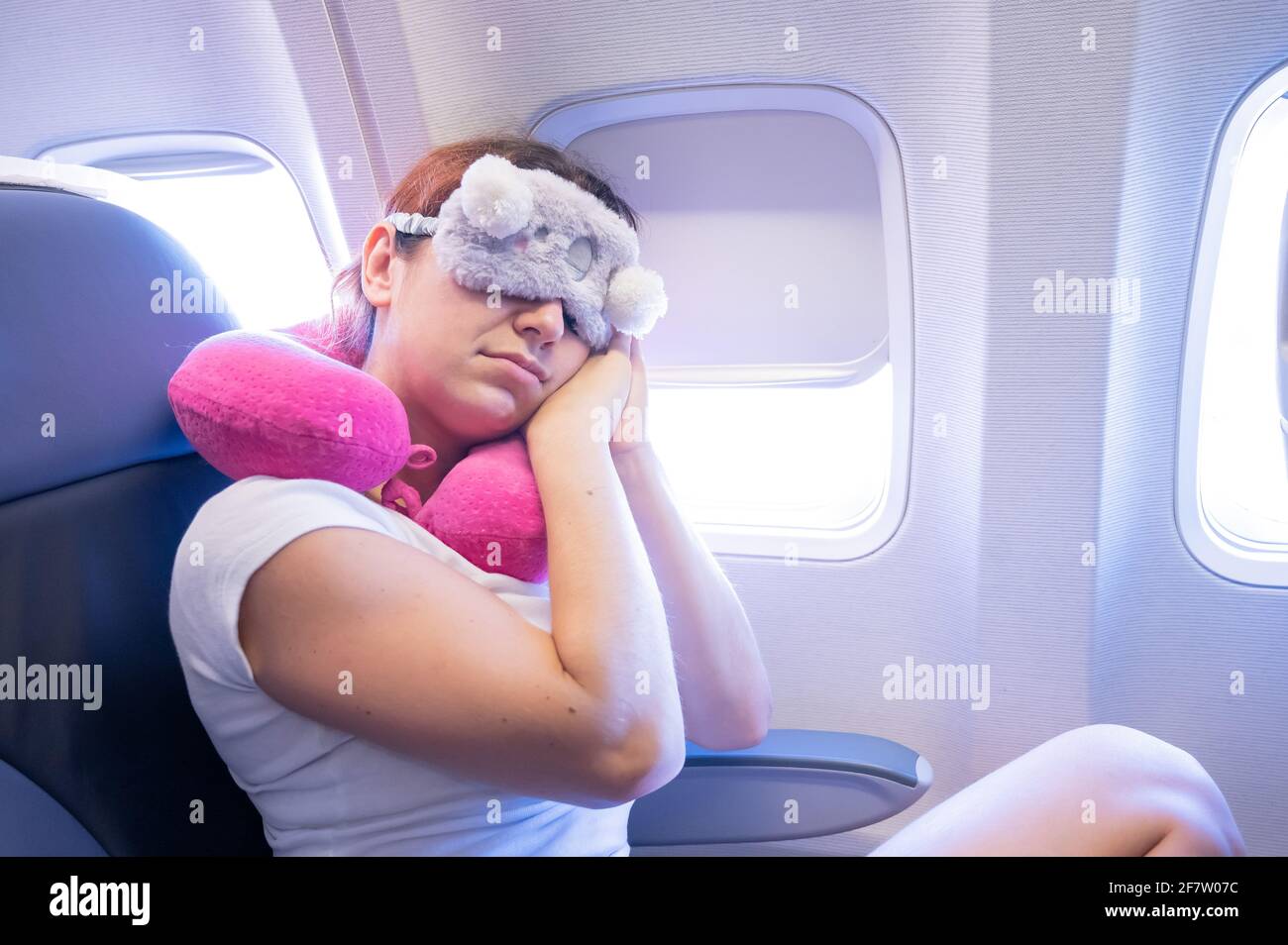Tired redhaired woman sleeping on the plane with an eye mask and a