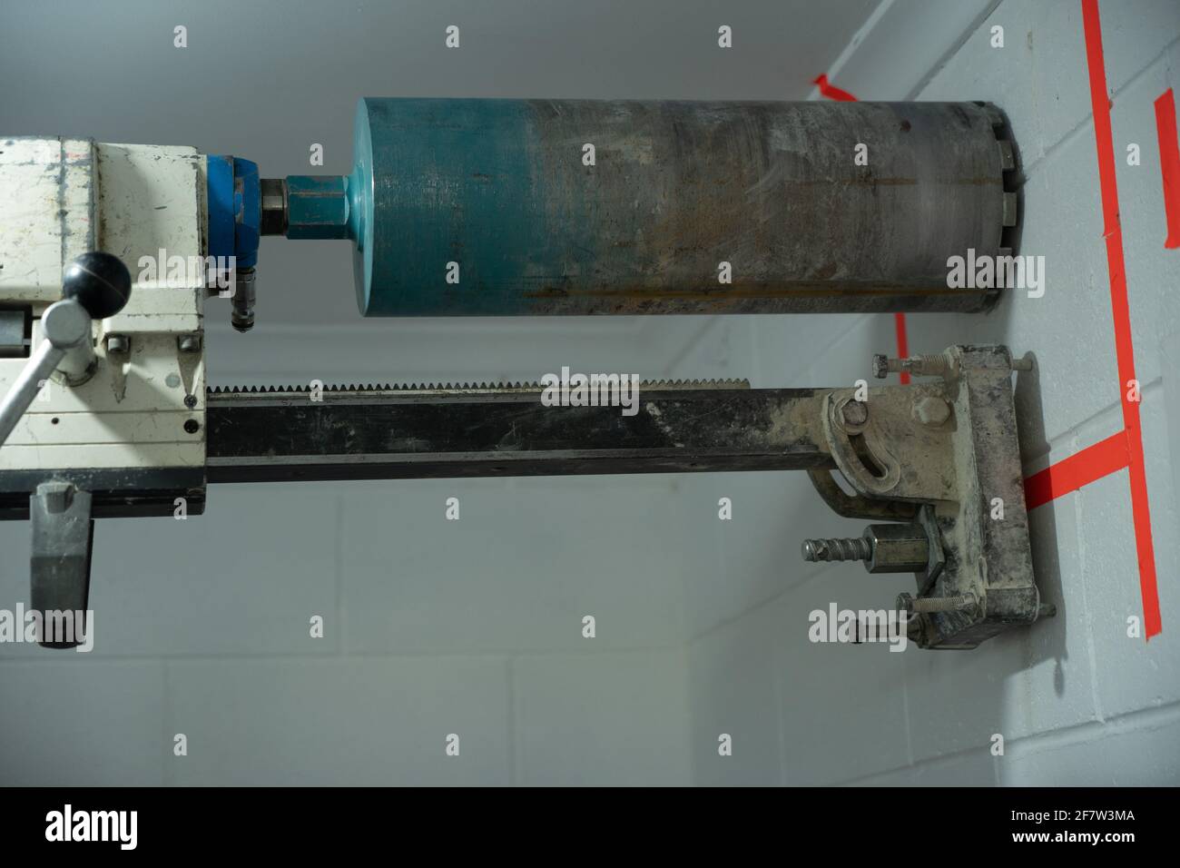 Concrete coring diamond cutting drill bolted to a white wall with an anchor bolt. Stock Photo