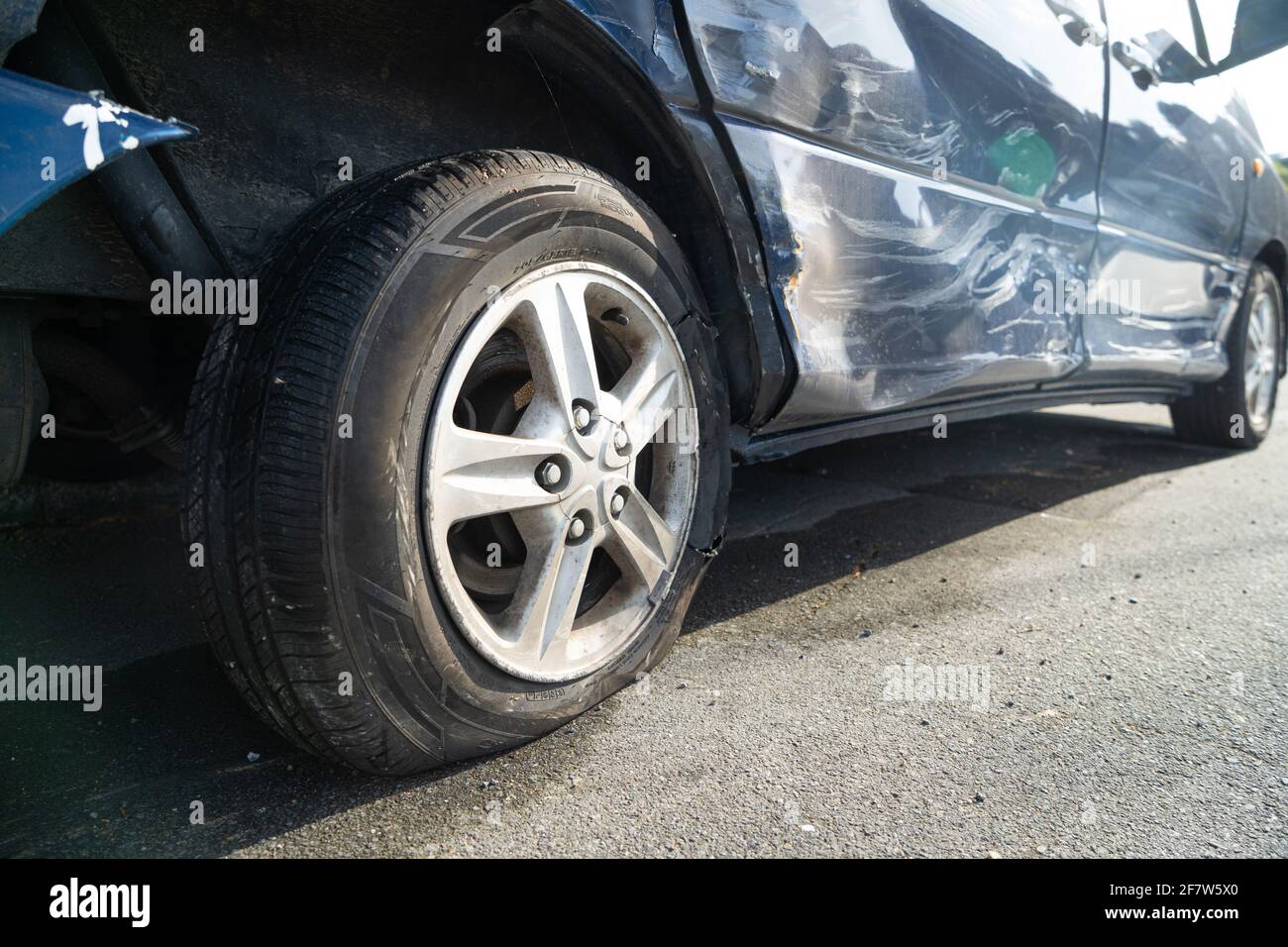 Close up of flat burst car tyre and damage to car bodywork after a car crash. Stock Photo