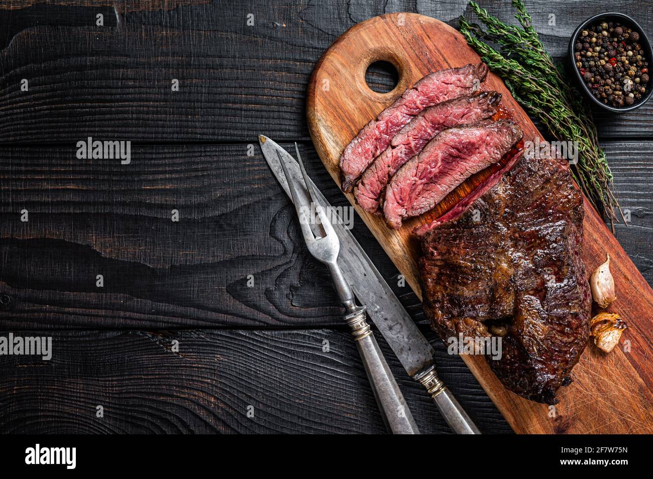 Grilled Butchers choice steak Onglet Hanging Tender beef meat on a cutting board. Black wooden background. Top View. Copy space Stock Photo