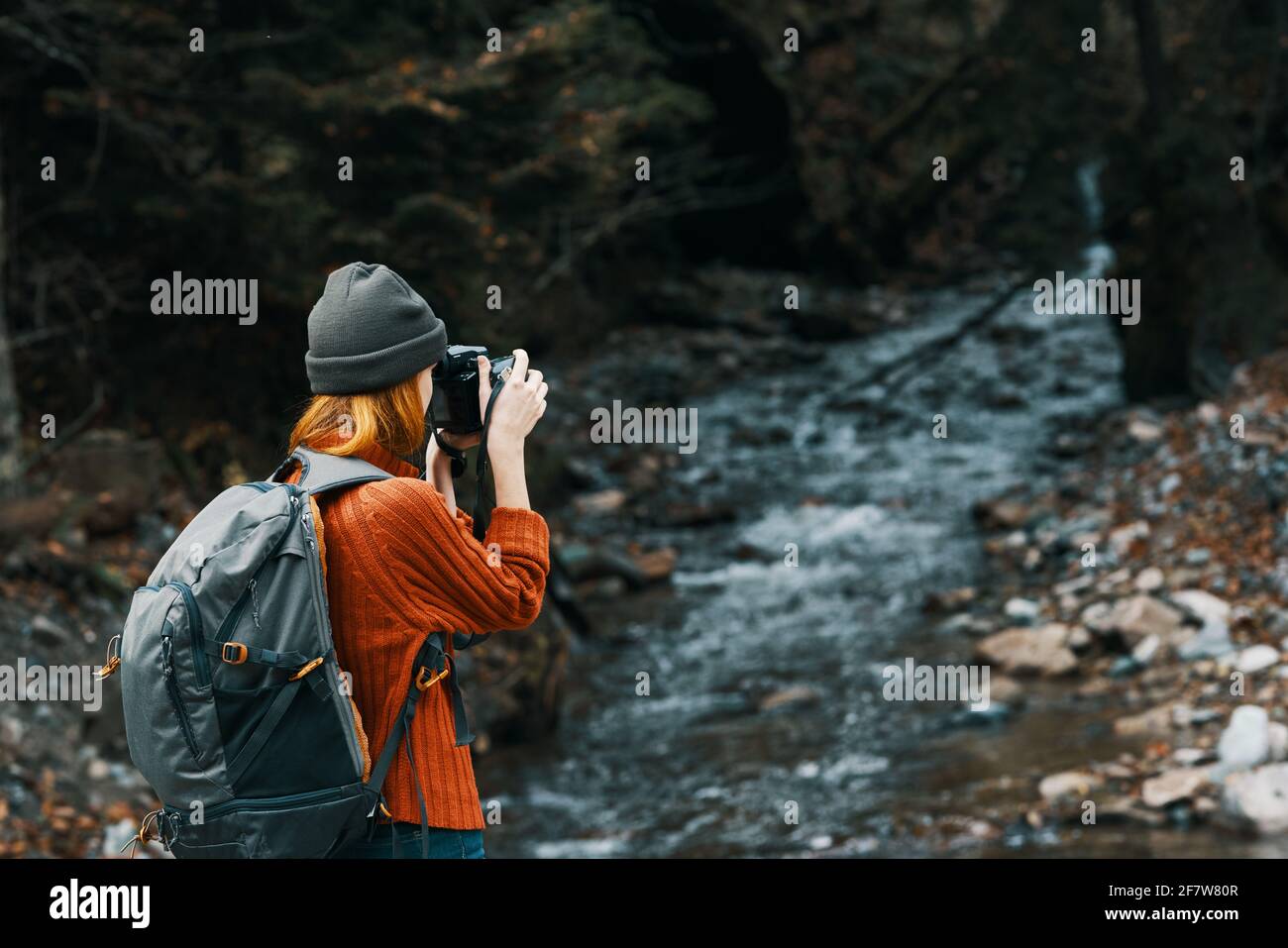 woman with a camera on nature in the mountains near the river and tall ...