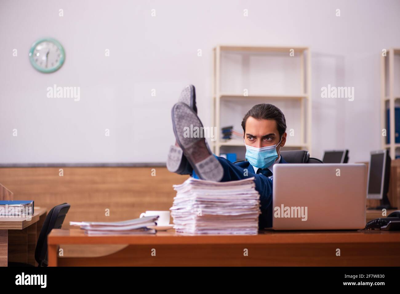 Young employee working in the office wearing mask Stock Photo - Alamy