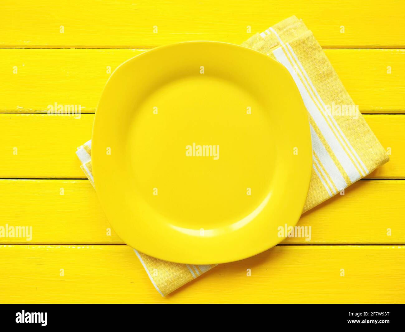 Empty yellow plate, napkin in white and yellow pattern on wooden background Stock Photo